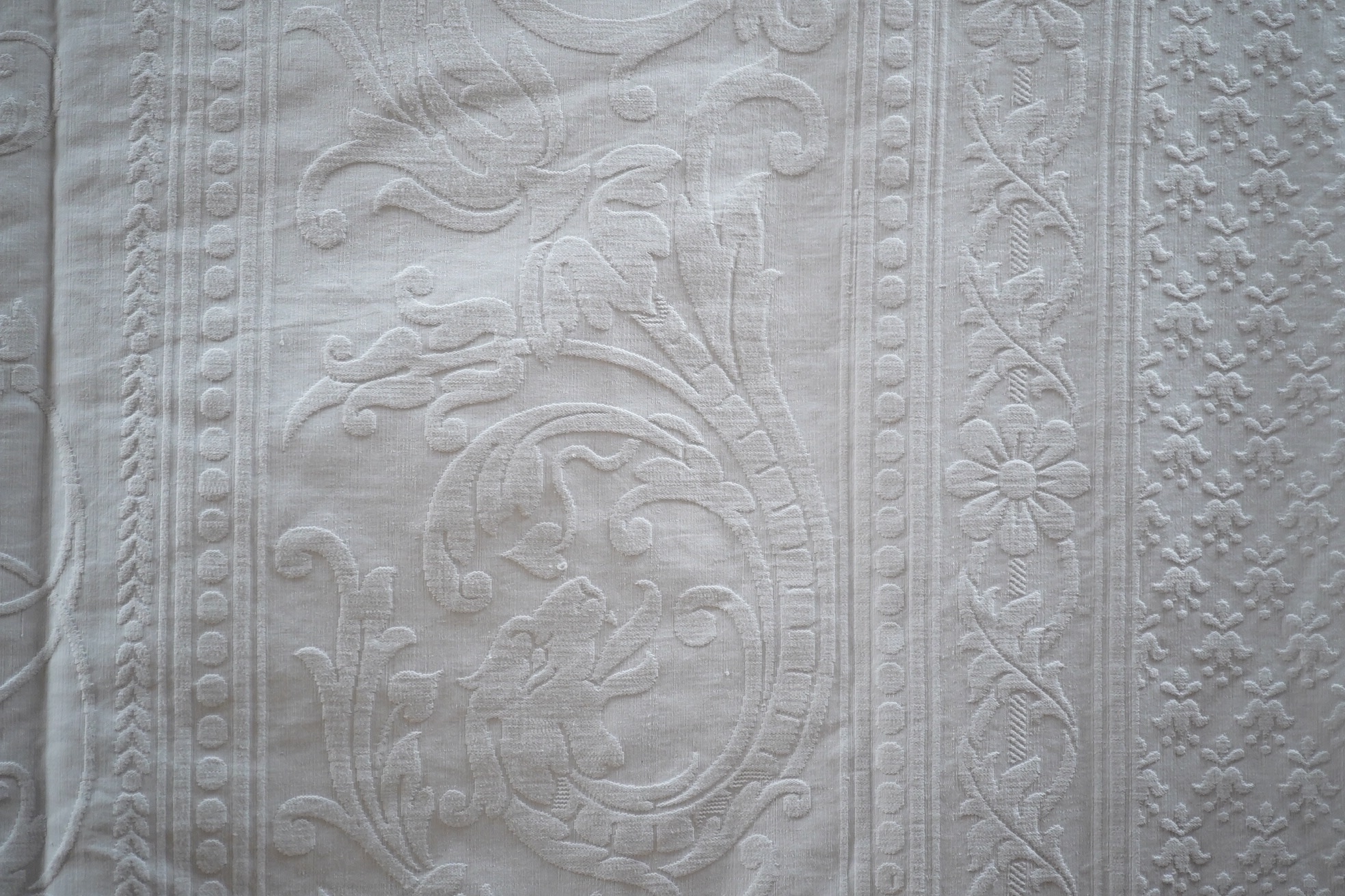 Three inspired Christopher Dresser white linen embossed bedcovers, with wide borders and ornate central designs, 216cm x 208cm. Condition - all good but will need rewashing.